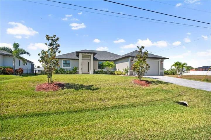 Prairie-style home with an attached garage, stucco siding, decorative driveway, and a front lawn