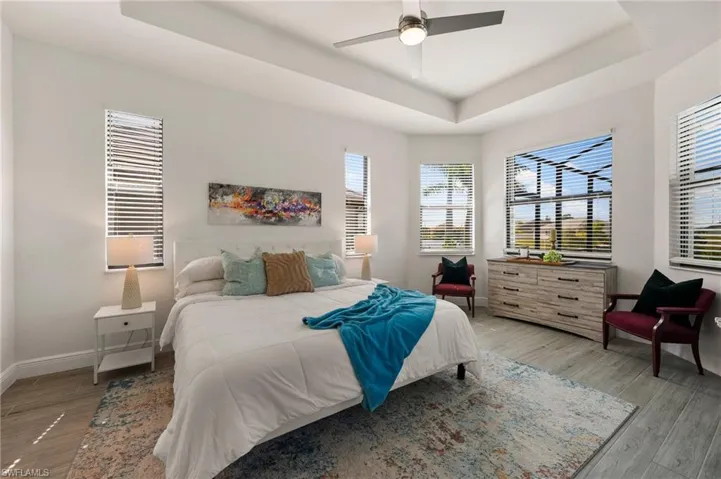 Bedroom featuring baseboards, a raised ceiling, ceiling fan, and wood finished floors