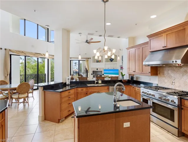 Kitchen featuring decorative light fixtures, range with two ovens, kitchen peninsula, and sink
