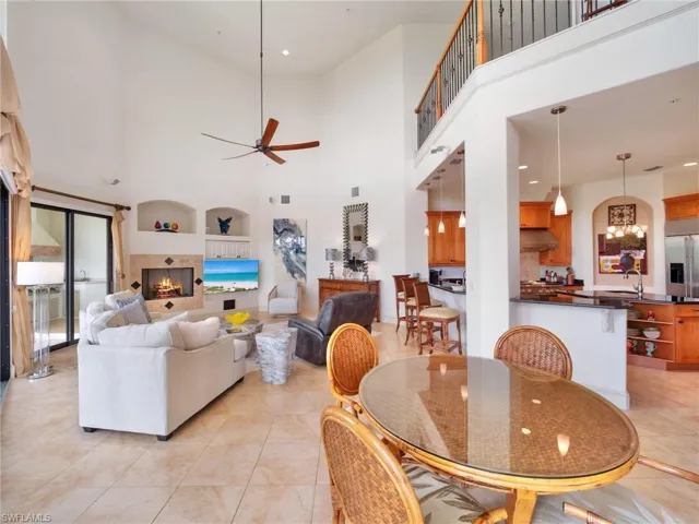 Dining space featuring a high ceiling, ceiling fan, a tile fireplace, recessed lighting, and built in shelves