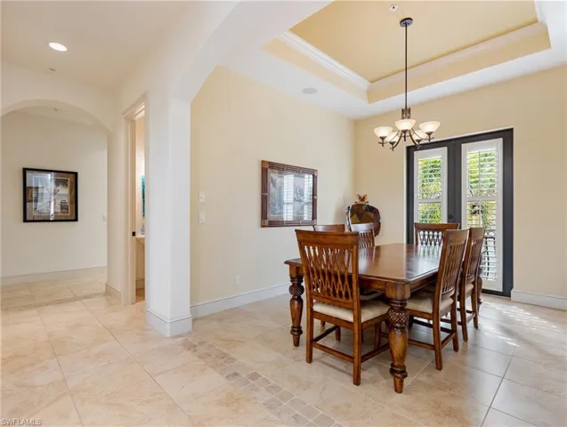 Dining area with a tray ceiling, crown molding, and an inviting chandelier