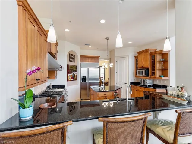 Kitchen featuring pendant lighting, a kitchen breakfast bar, high end appliances, and kitchen peninsula