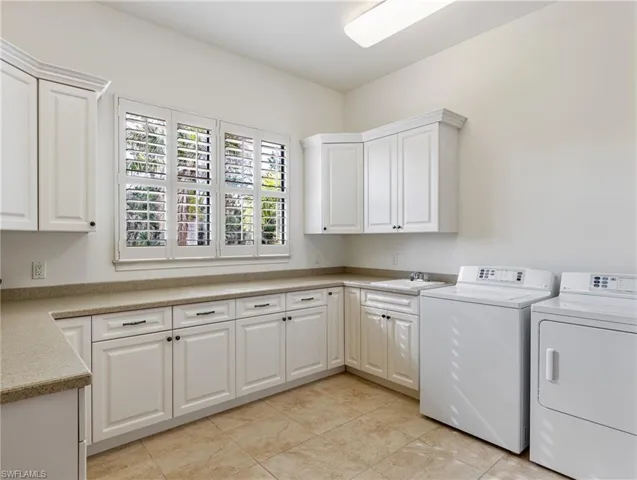 Laundry room featuring washing machine and clothes dryer, plenty of natural light, cabinets, and sink