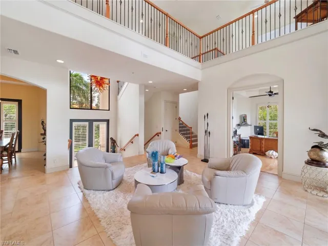 Living room featuring arched walkways, a towering ceiling, recessed lighting, light tile patterned flooring, and stairs