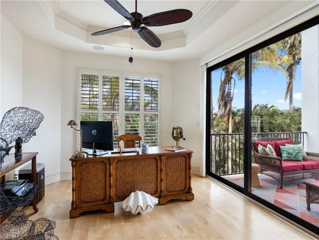 Home office featuring a raised ceiling, ceiling fan, light hardwood / wood-style flooring, and ornamental molding