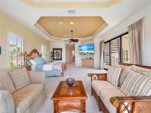 Carpeted bedroom featuring a raised ceiling and access to outside