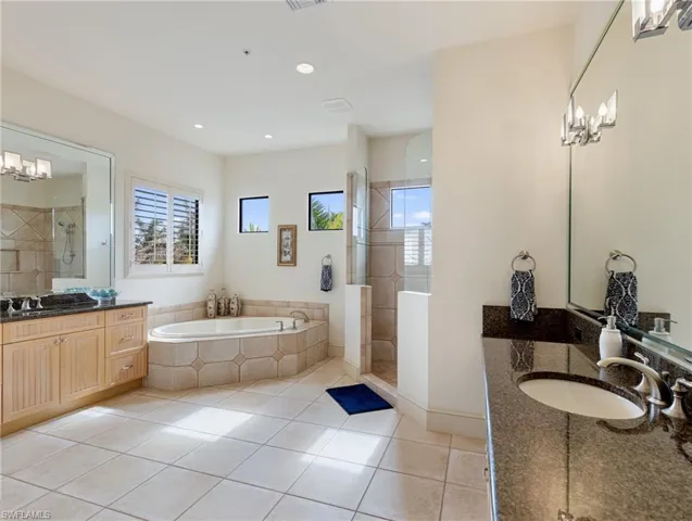 Bathroom with tile patterned floors, vanity, and plus walk in shower
