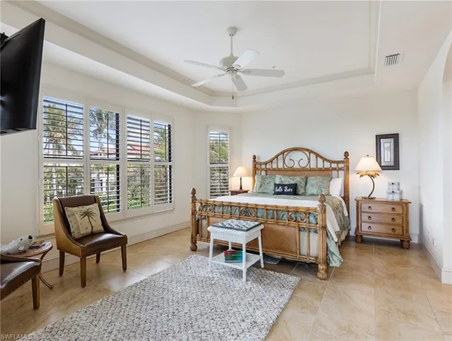 Bedroom with ceiling fan, a raised ceiling, and crown molding