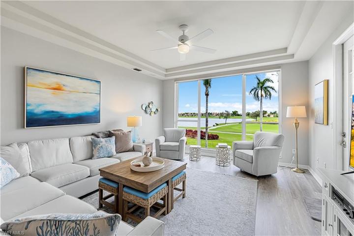 Living Area with Panoramic views of the Golf Course overlooking the 16th hole & Lake from the grand picture window! LVP throughout living areas. Coastal decor and Trey Ceiling.
