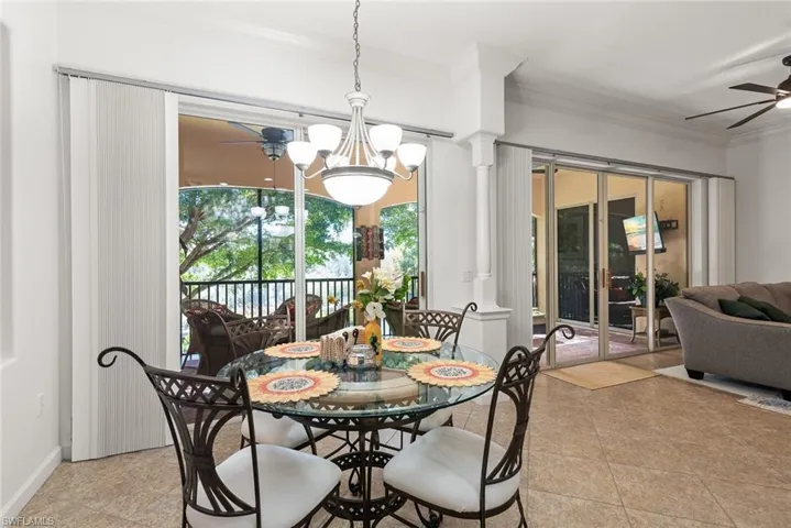 Dining room with a ceiling fan, a chandelier, crown molding, and ornate columns