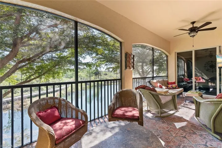 Sunroom with lofted ceiling, a water view, and ceiling fan