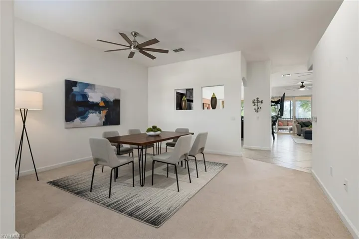 Dining room with ceiling fan, light carpet, and light tile patterned flooring