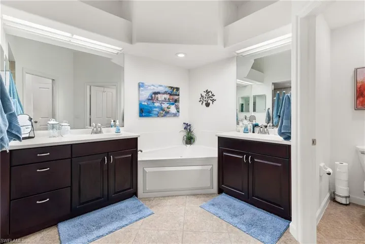 Bathroom with a sink, tile patterned flooring, two vanities, and a bath
