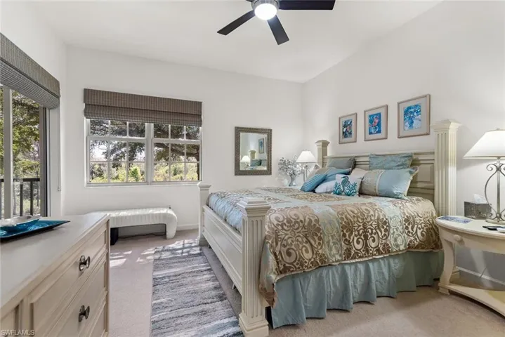 Carpeted bedroom with ceiling fan and multiple windows