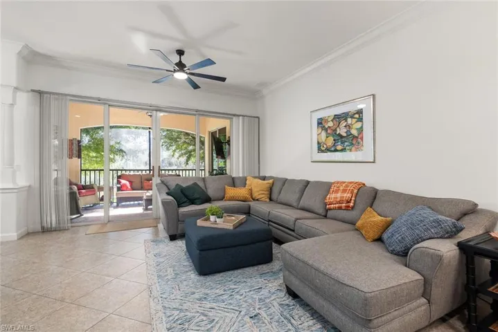Living room featuring ornamental molding, light tile patterned floors, and ceiling fan
