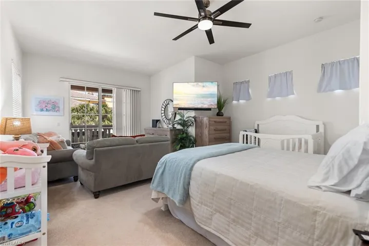 Bedroom featuring a ceiling fan, access to outside, light carpet, and vaulted ceiling