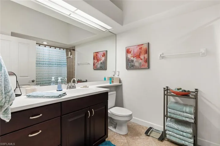 Bathroom with toilet, vanity, a shower with curtain, baseboards, and tile patterned floors