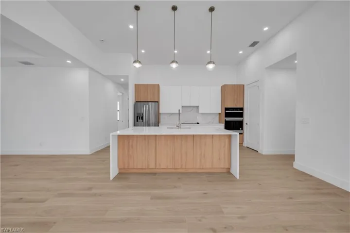 Unfurnished living room featuring a tray ceiling, recessed lighting, a ceiling fan, light wood-style flooring, and a towering ceiling