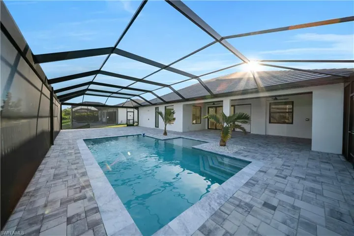 View of swimming pool with glass enclosure, a patio area, and a pool with connected hot tub