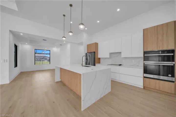 Kitchen featuring modern cabinets, open floor plan, light wood-type flooring, and recessed lighting