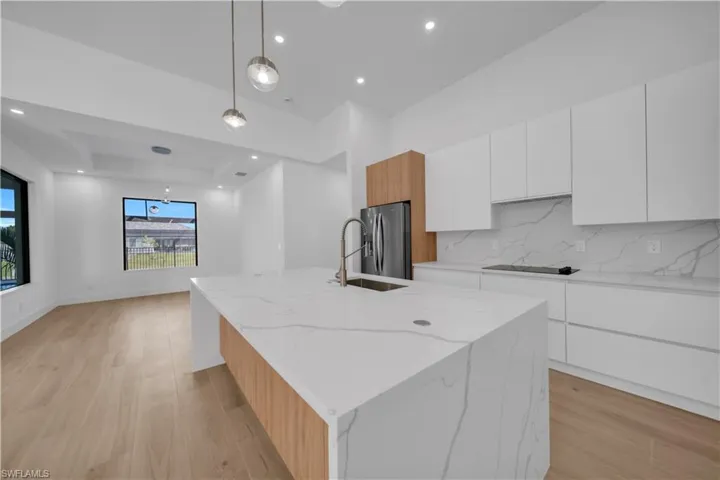 Empty room featuring a raised ceiling, light wood-style floors, and recessed lighting