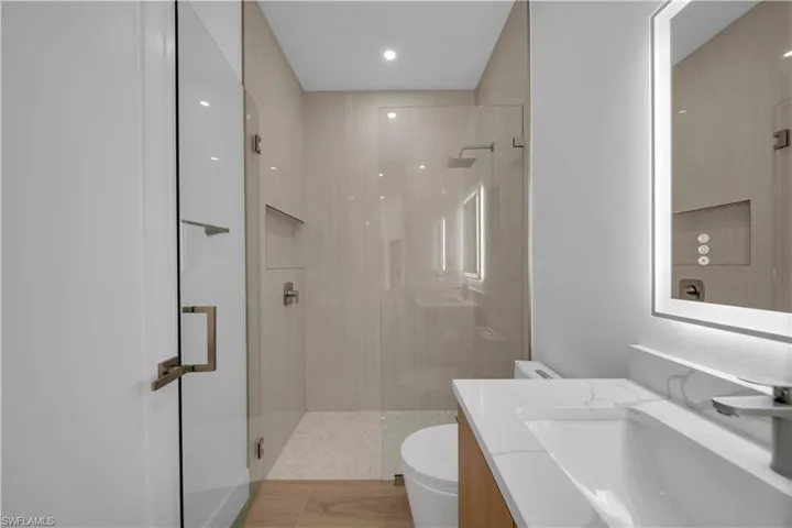 Spare room featuring a raised ceiling, light wood-style flooring, a ceiling fan, and recessed lighting