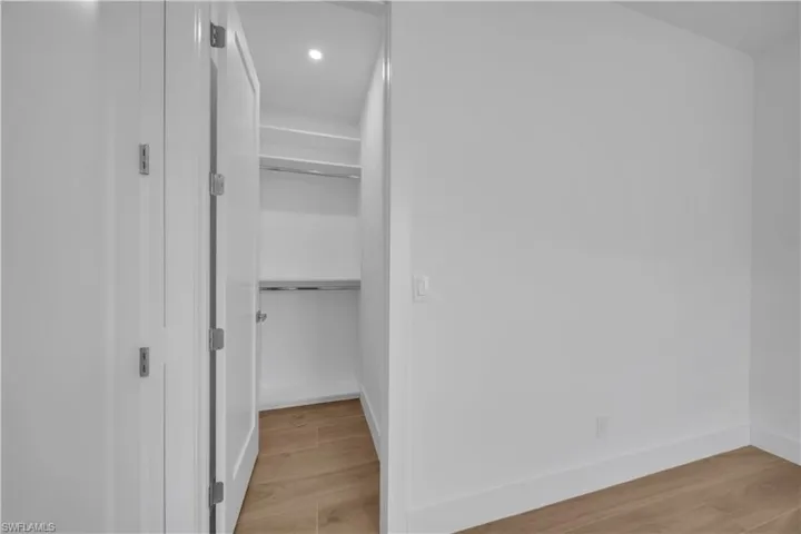 Full bath featuring a tile shower, vanity, recessed lighting, and wood finished floors