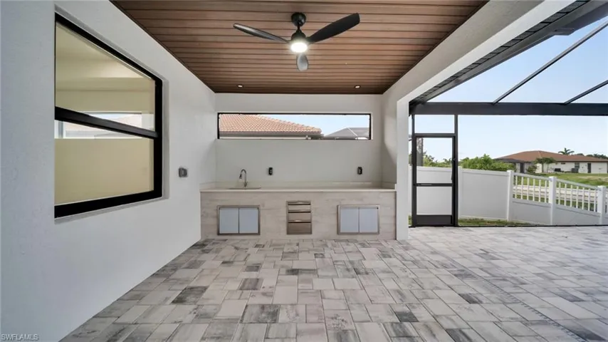 View of patio featuring ceiling fan, exterior kitchen, and glass enclosure