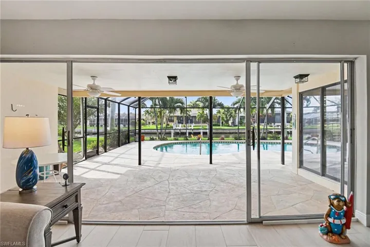 View of swimming pool featuring a sunroom, ceiling fan, and a residential view