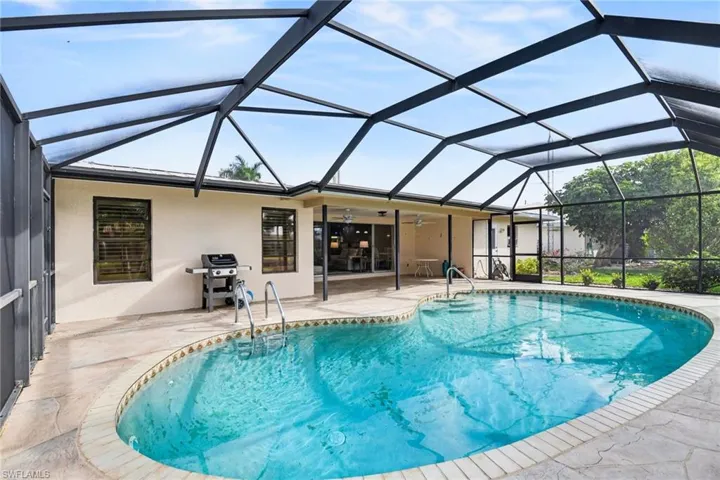 Swimming pool featuring a sunroom, glass enclosure, a patio, and area for grilling