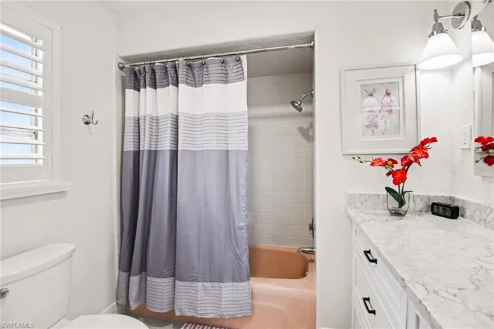 Bathroom featuring vanity, shower / bath combination with curtain, and plenty of natural light