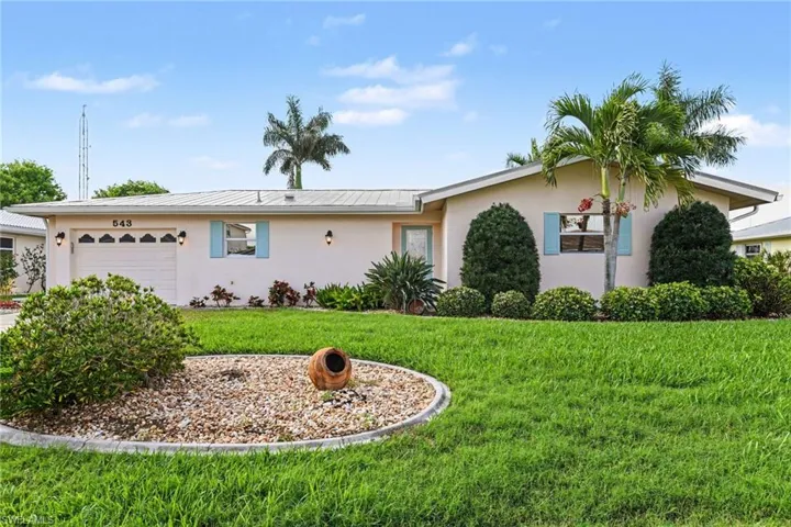 Single story home featuring stucco siding, a garage, a front yard, and a metal roof