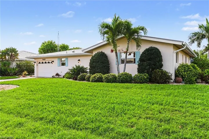 Single story home featuring stucco siding, a garage, a front yard, and driveway