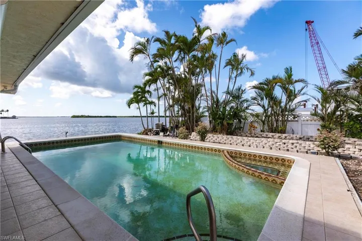 View of swimming pool featuring a water view and a pool with connected hot tub