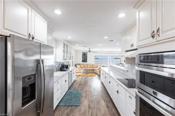Kitchen featuring appliances with stainless steel finishes, dark wood finished floors, white cabinetry, under cabinet range hood, and recessed lighting