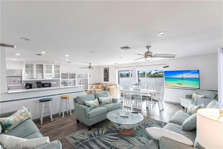 Living area with wood finished floors, a ceiling fan, recessed lighting, and a textured ceiling