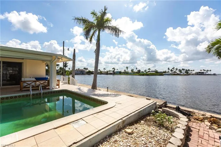 Swimming pool with a patio area and a water view
