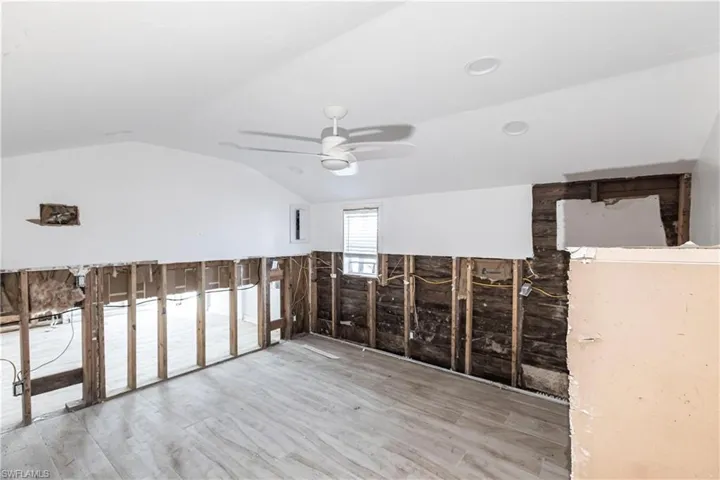 Additional living space featuring vaulted ceiling, wood finished floors, and a ceiling fan