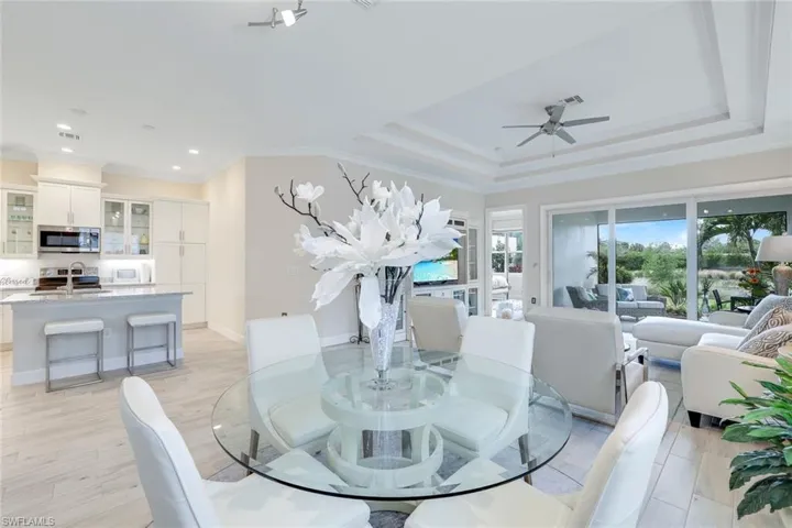 Dining space featuring ceiling fan, sink, light hardwood / wood-style flooring, crown molding, and a tray ceiling