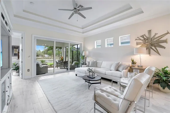 Living room with a tray ceiling, ceiling fan, and ornamental molding