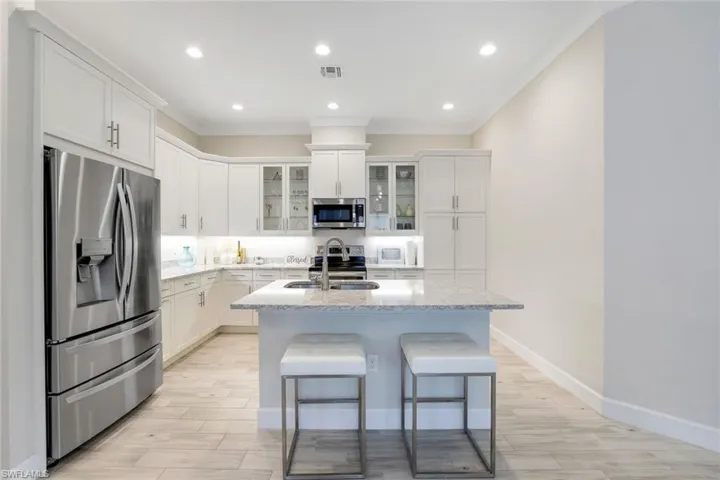 Kitchen with white cabinets, sink, an island with sink, and appliances with stainless steel finishes
