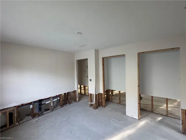 Interior space featuring exposed wall framing, unfinished concrete flooring, and ceiling-mounted light fixture rough-ins