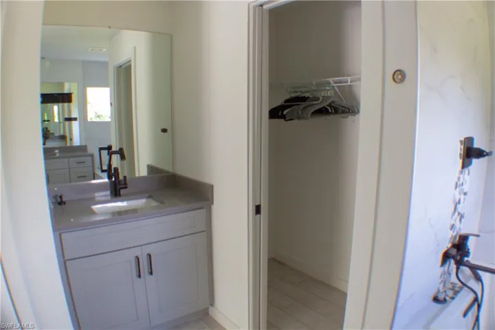 Bathroom vanity with a light gray cabinet, a gray countertop, and a matte black faucet