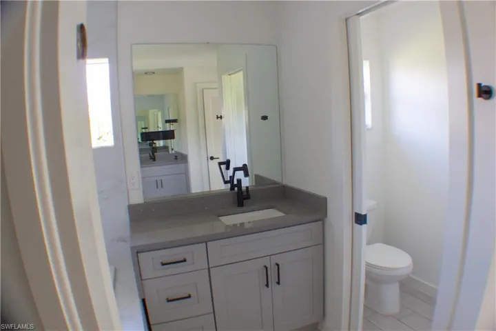 Bathroom vanity featuring a light gray cabinet with matte black hardware, integrated sink, and speckled countertop