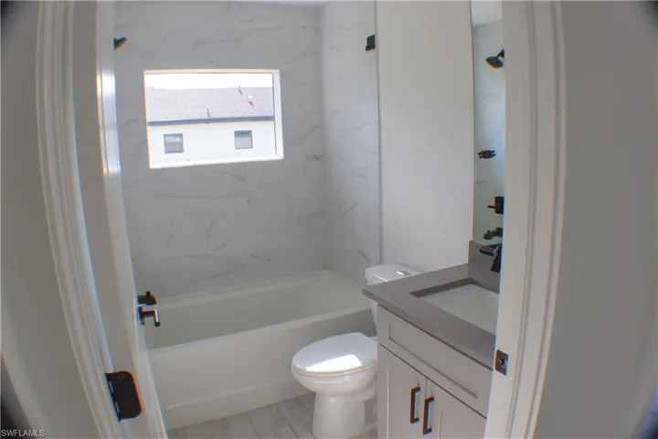 Bathroom featuring white subway tile bath surround, built-in bathtub, and a window above the tub