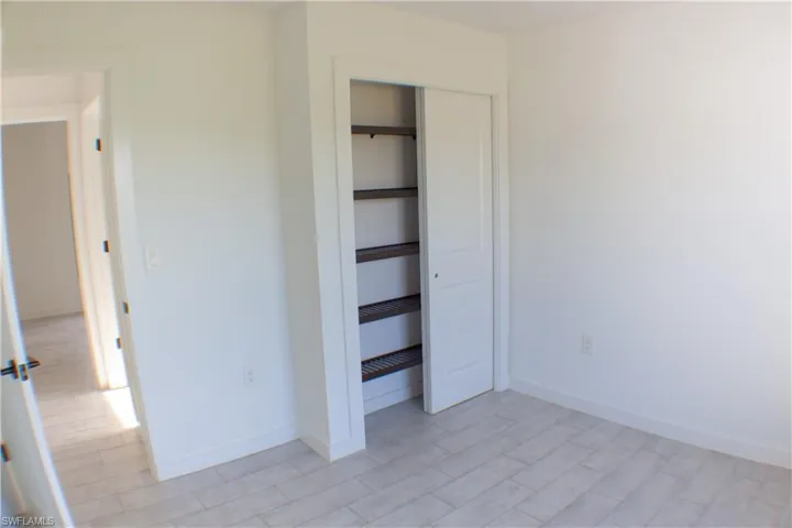 Room featuring light-toned plank-style flooring, white walls, and a closet with bifold doors and built-in shelving