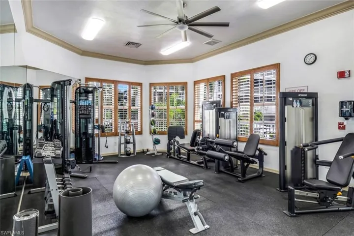Workout area featuring a ceiling fan, ornamental molding, and baseboards