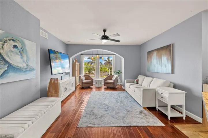 Living area with a textured wall, ceiling fan, hardwood / wood-style flooring, and arched walkways
