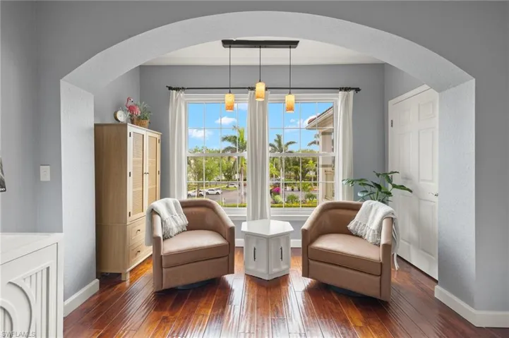 Sitting room with arched walkways and dark wood-type flooring