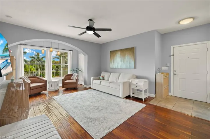 Living area featuring light wood finished floors, a ceiling fan, and arched walkways